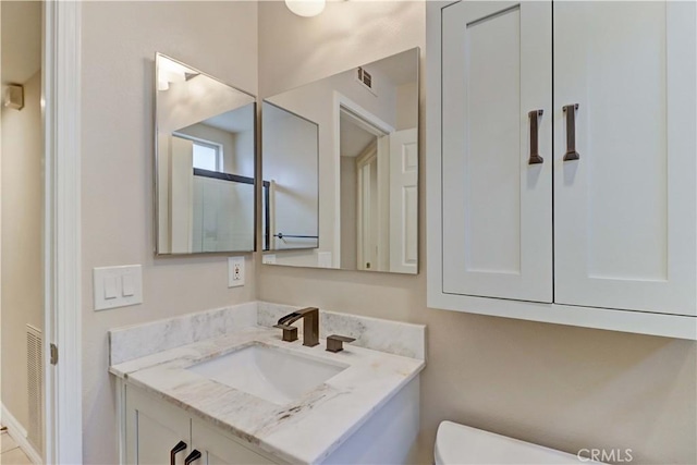 bathroom with toilet, visible vents, and vanity