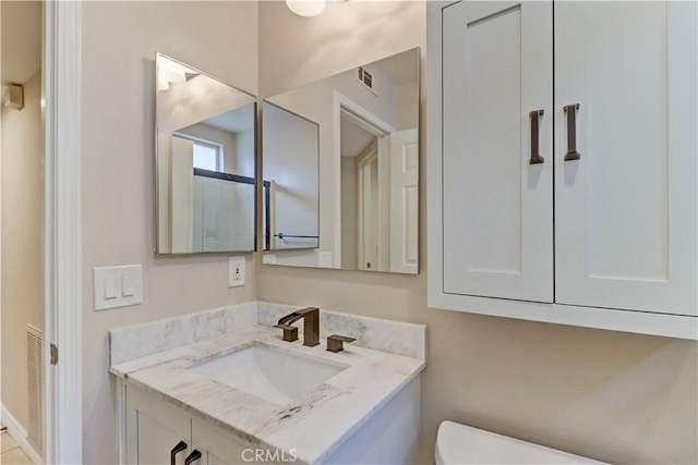 half bath with vanity, visible vents, and toilet