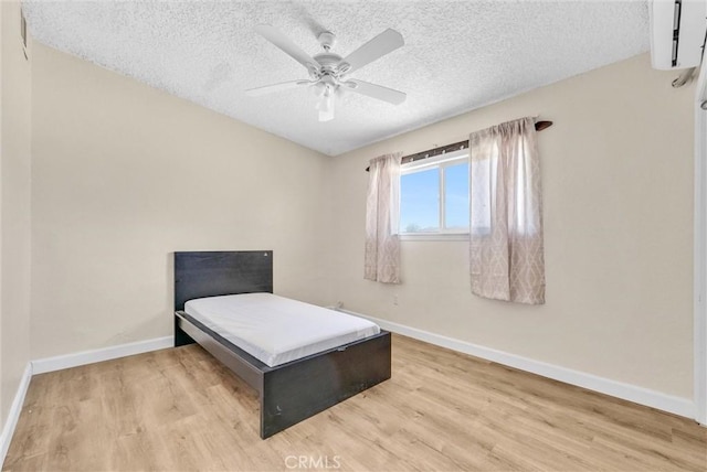 bedroom with ceiling fan, light wood-type flooring, and a textured ceiling