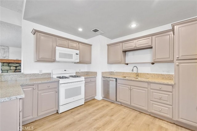 kitchen featuring sink, white appliances, light stone counters, and light hardwood / wood-style floors