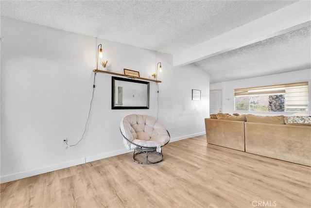 unfurnished room with a textured ceiling, lofted ceiling with beams, and light hardwood / wood-style flooring