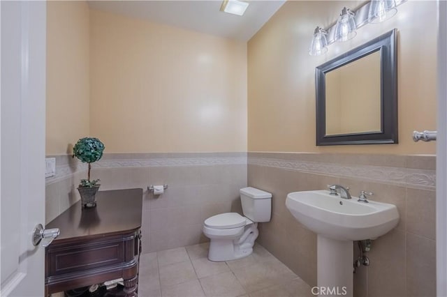 bathroom featuring tile patterned floors, sink, tile walls, and toilet