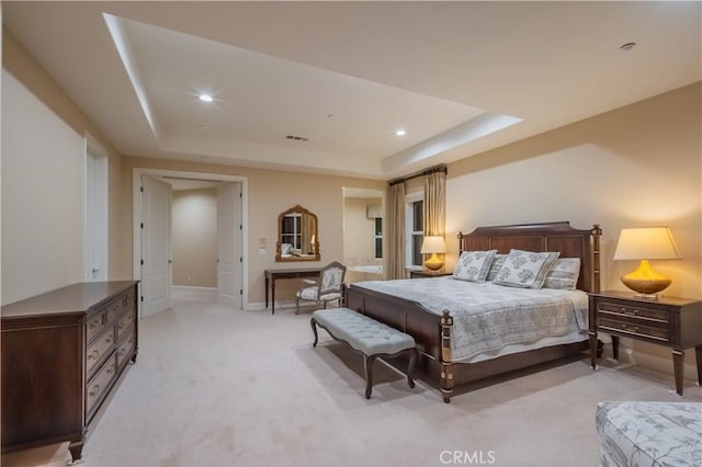 bedroom with a raised ceiling and light carpet