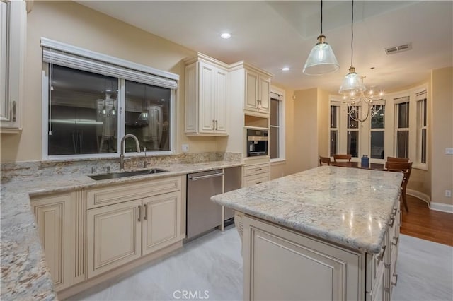 kitchen with light stone counters, cream cabinets, stainless steel dishwasher, pendant lighting, and sink