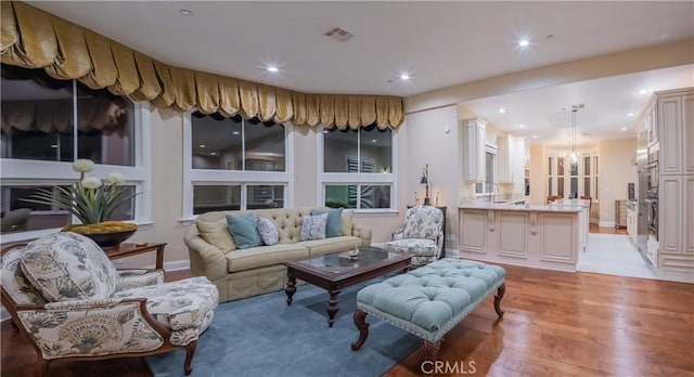 living room with sink, light hardwood / wood-style floors, and a chandelier