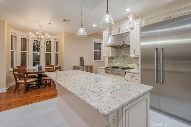 kitchen with appliances with stainless steel finishes, a kitchen island, hanging light fixtures, and white cabinets