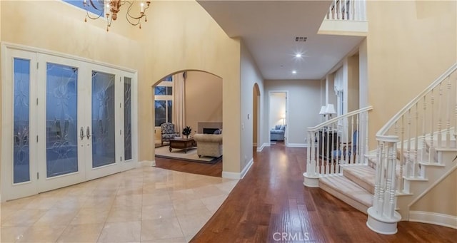 foyer with hardwood / wood-style flooring, french doors, and a notable chandelier