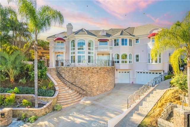 mediterranean / spanish-style home featuring a garage and a balcony