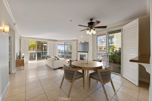 dining room with a wealth of natural light, a glass covered fireplace, light tile patterned flooring, and crown molding