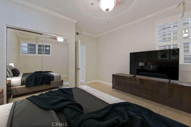 bedroom with a closet, visible vents, ornamental molding, light tile patterned flooring, and baseboards