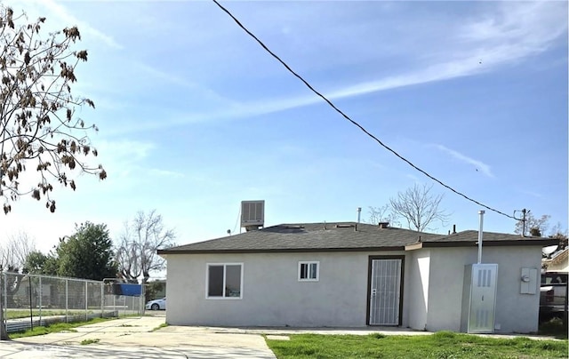 back of property with a yard and central AC