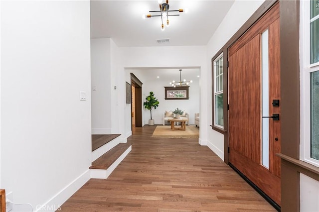 entrance foyer featuring baseboards, wood finished floors, visible vents, and an inviting chandelier