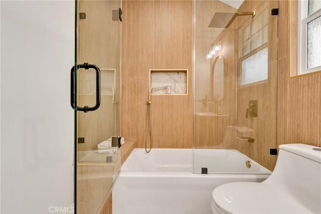 bathroom with toilet and shower / bath combination with glass door