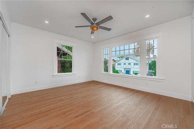 empty room featuring a wealth of natural light, light wood-type flooring, baseboards, and recessed lighting