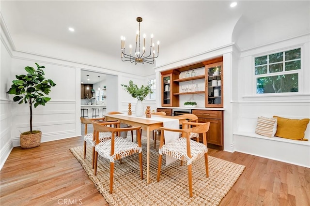 dining room featuring light wood-type flooring, a chandelier, a decorative wall, and recessed lighting