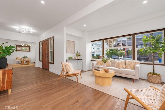 living area with recessed lighting, an inviting chandelier, baseboards, and wood finished floors