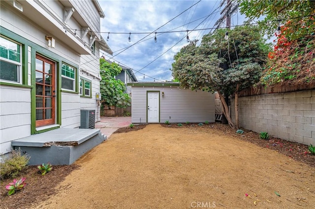 view of yard with cooling unit, a fenced backyard, and an outdoor structure