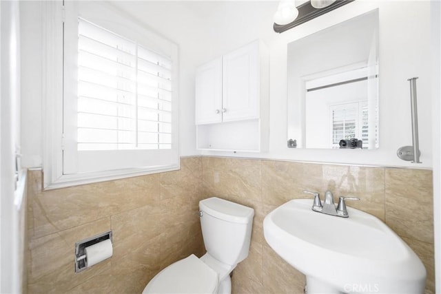 half bath featuring toilet, tile walls, and a sink