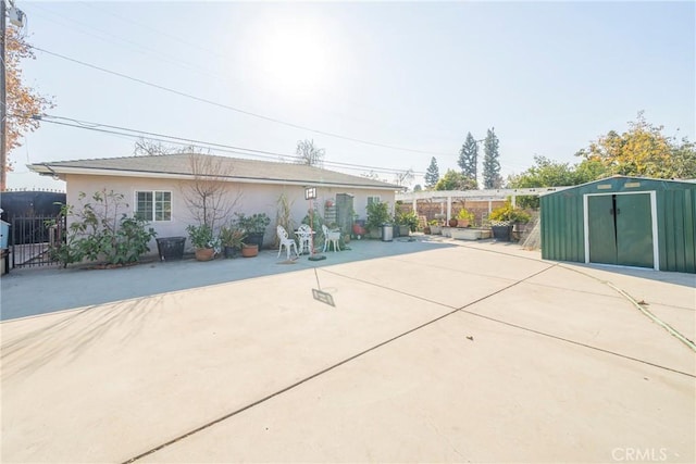 exterior space with an outbuilding, a patio, a storage shed, and fence