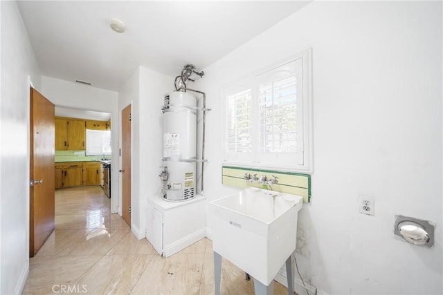 laundry area with water heater, baseboards, and a sink