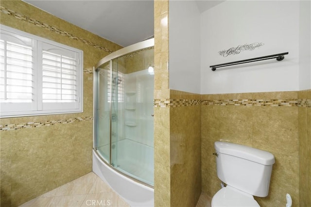 full bath featuring toilet, a wainscoted wall, tile patterned flooring, and tile walls