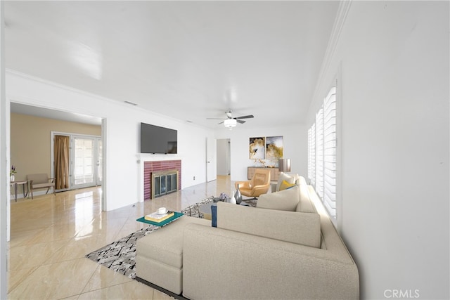 living area with a ceiling fan, a brick fireplace, and crown molding