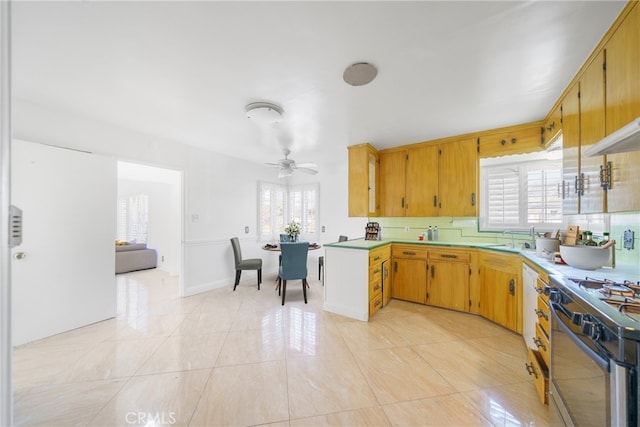 kitchen featuring gas stove, light countertops, a sink, and light tile patterned floors