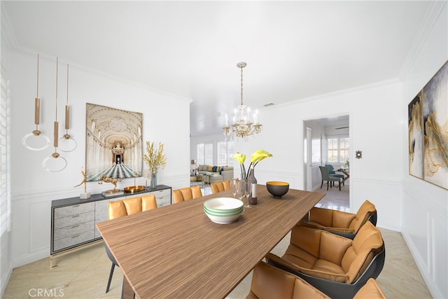 dining area featuring an inviting chandelier, a decorative wall, crown molding, and a wainscoted wall