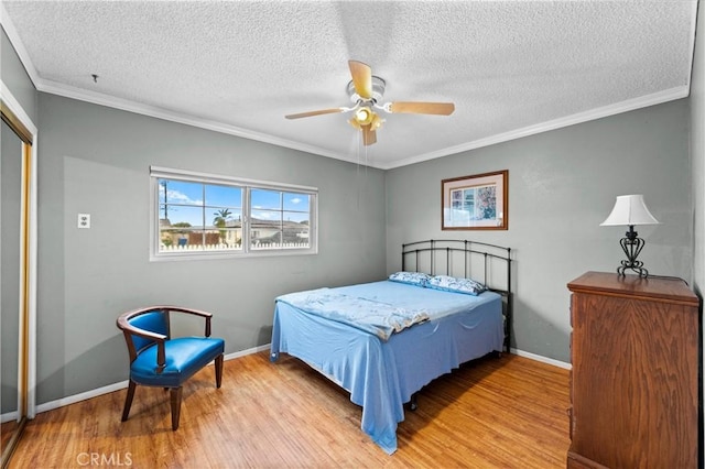 bedroom with ceiling fan, a textured ceiling, wood finished floors, baseboards, and crown molding