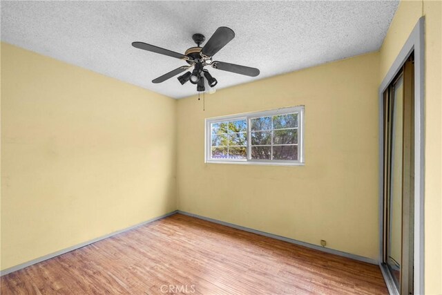 spare room with ceiling fan, a textured ceiling, and wood finished floors