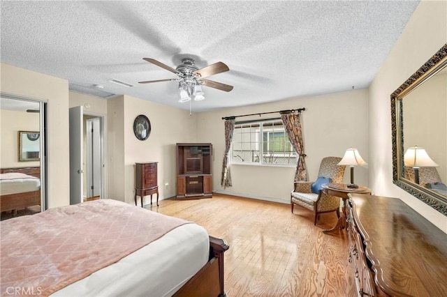 bedroom featuring visible vents, ceiling fan, a textured ceiling, and wood finished floors