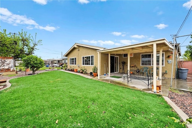 back of house featuring a patio, a lawn, and stucco siding