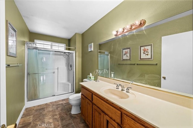 bathroom with vanity, a shower stall, toilet, and baseboards