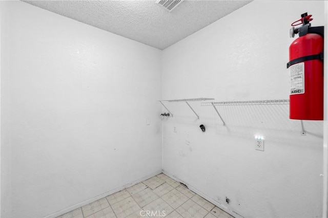 washroom featuring laundry area, visible vents, a textured ceiling, and light floors