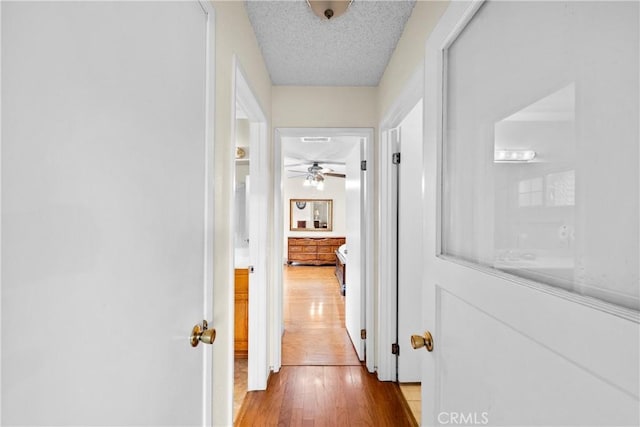 hall with a textured ceiling and wood finished floors