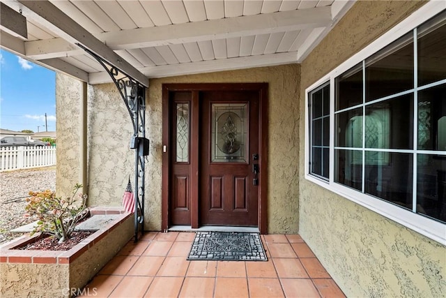 entrance to property with fence and stucco siding