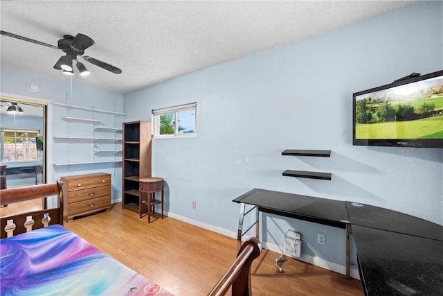 bedroom with a ceiling fan, a textured ceiling, baseboards, and wood finished floors