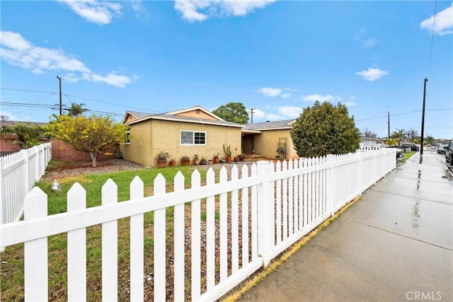 single story home with a fenced front yard and stucco siding