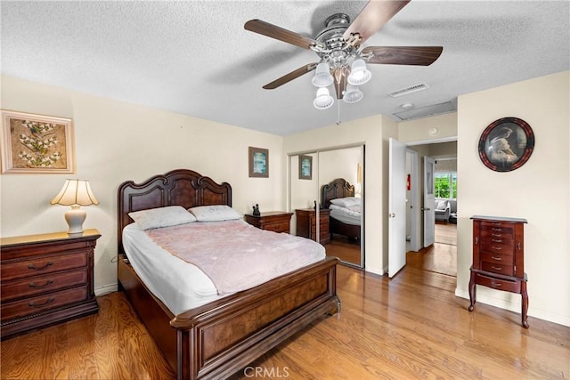 bedroom featuring a textured ceiling, a closet, visible vents, and light wood-style floors