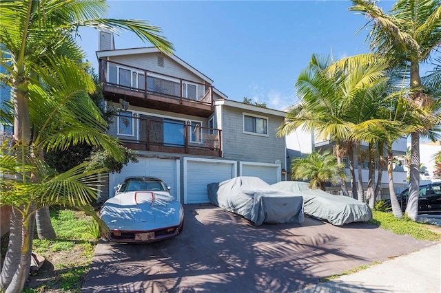 view of front facade featuring driveway, a balcony, and a garage