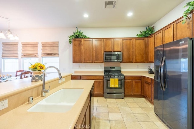 kitchen featuring decorative light fixtures, sink, light tile patterned floors, appliances with stainless steel finishes, and a chandelier