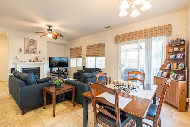 tiled dining space with ceiling fan with notable chandelier