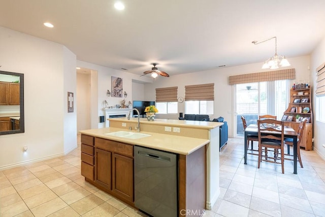 kitchen featuring a kitchen island with sink, decorative light fixtures, black dishwasher, sink, and ceiling fan with notable chandelier