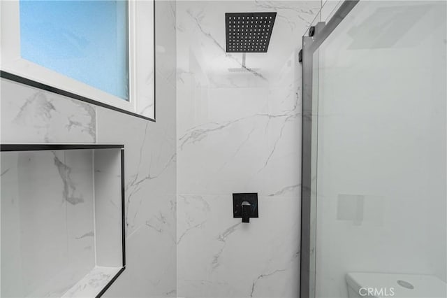 bathroom featuring toilet and a marble finish shower