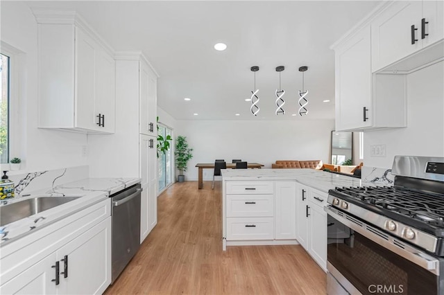 kitchen featuring light stone counters, decorative light fixtures, appliances with stainless steel finishes, white cabinets, and a peninsula