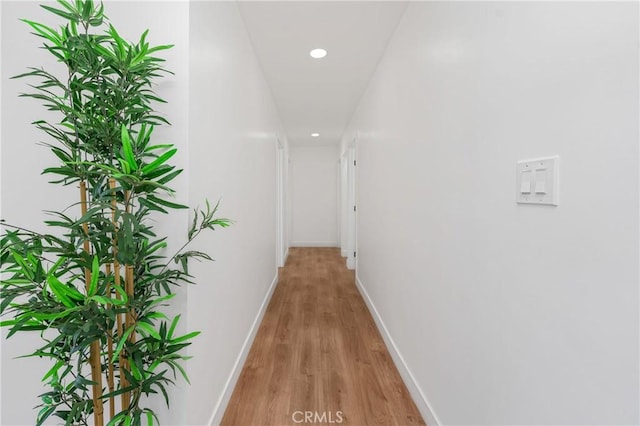 corridor featuring light wood finished floors, recessed lighting, and baseboards