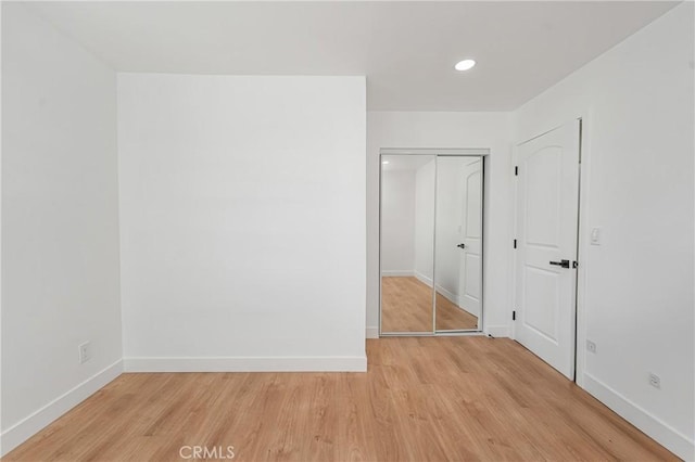 unfurnished bedroom with light wood-type flooring, a closet, baseboards, and recessed lighting