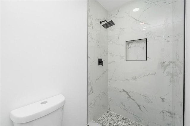 bathroom featuring a marble finish shower and toilet