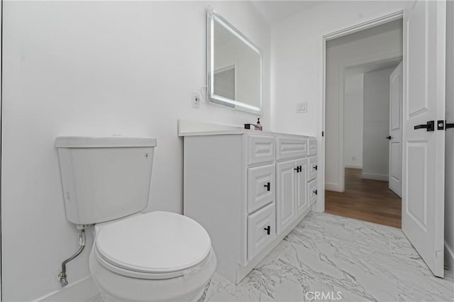 bathroom with marble finish floor, baseboards, vanity, and toilet