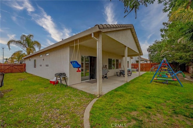 back of property with a yard, a playground, and a patio area